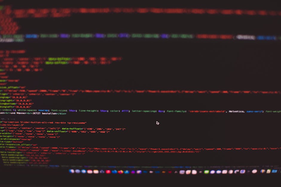 A computer screen displaying a blurred image of a coding interface with lines of HTML and CSS code in various colors, including red, green, blue, and purple, against a predominantly black background. 